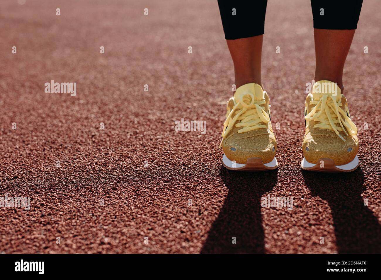 Primo piano di piedi femminili in sneakers gialle allo stadio Foto Stock