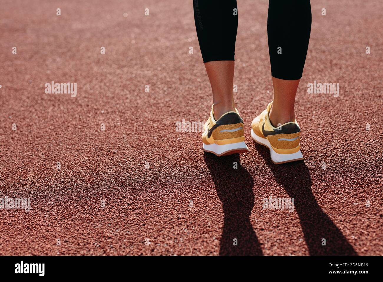 Vista posteriore della donna in sneakers sportive in piedi in rosso campo Foto Stock