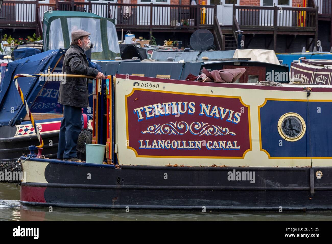 uomo al timone o timone di un canale tradizionale barca stretta ot chiatta sul canale grand union a stoke bruerne nel northamptonshire, regno unito Foto Stock