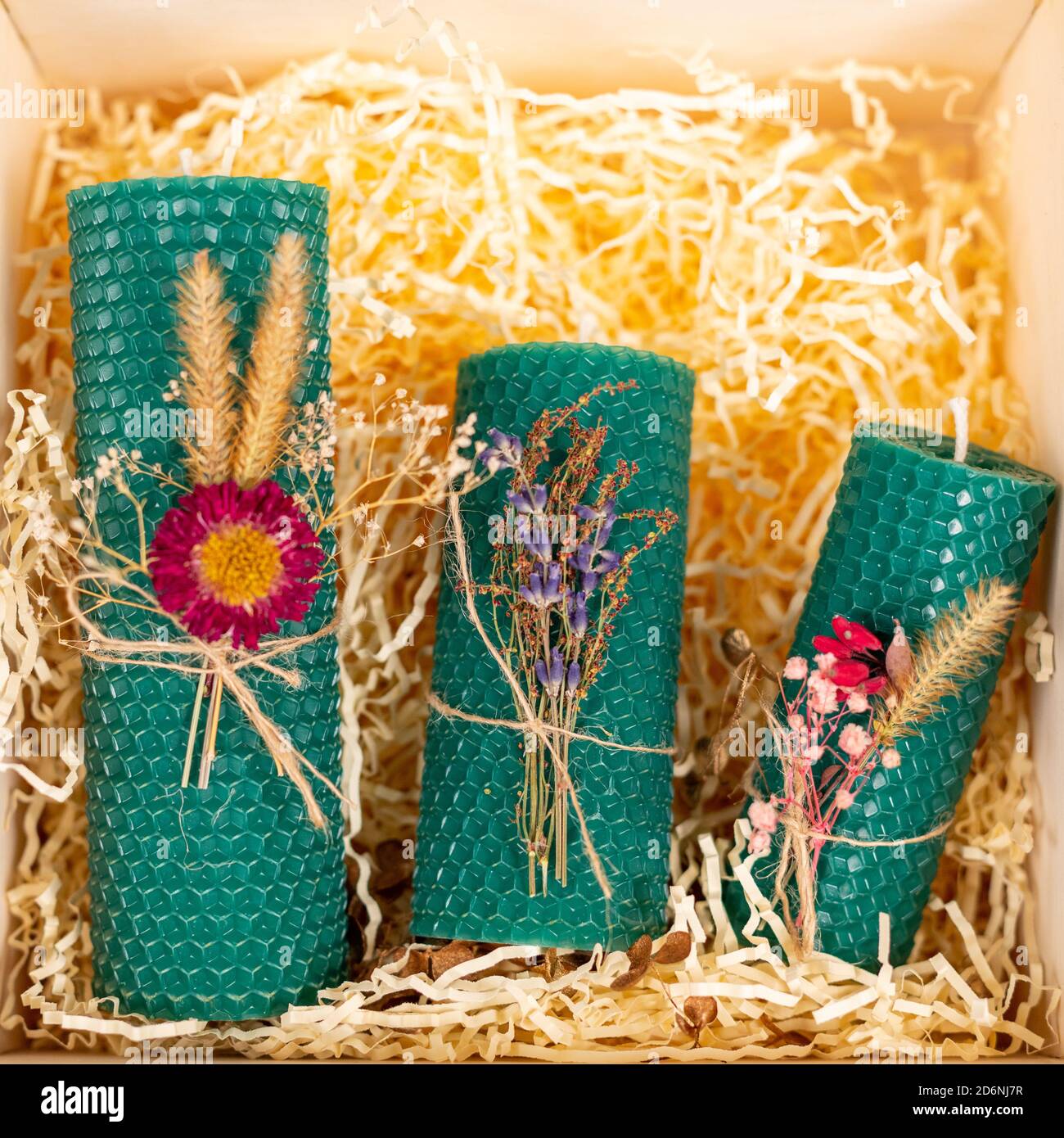 Candele di miele verde fatte a mano da cera naturale in una scatola regalo su uno sfondo di lana di legno. Elementi di materiali naturali. Natale o Capodanno Foto Stock