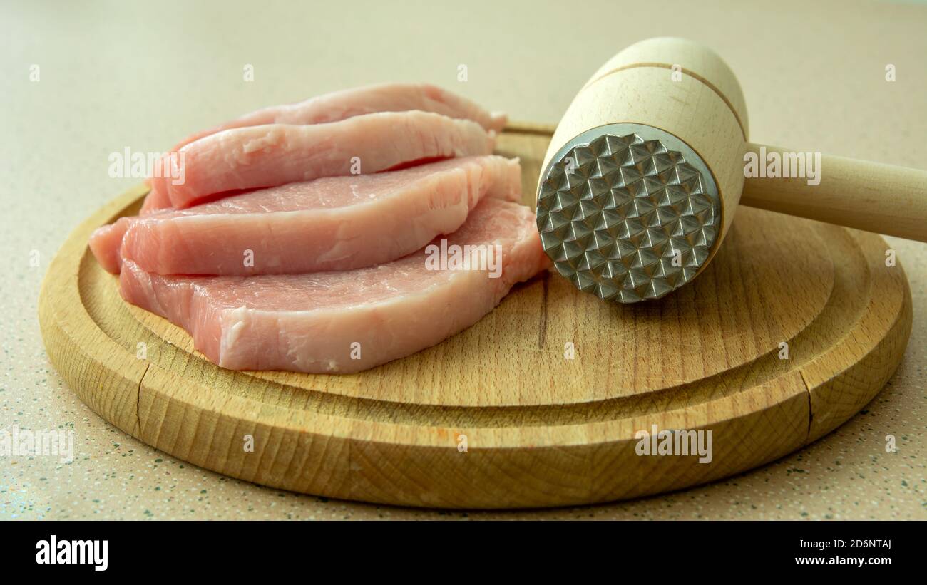 Pezzi grezzi di lombo su una tavola e una carne mazzuolo Foto Stock