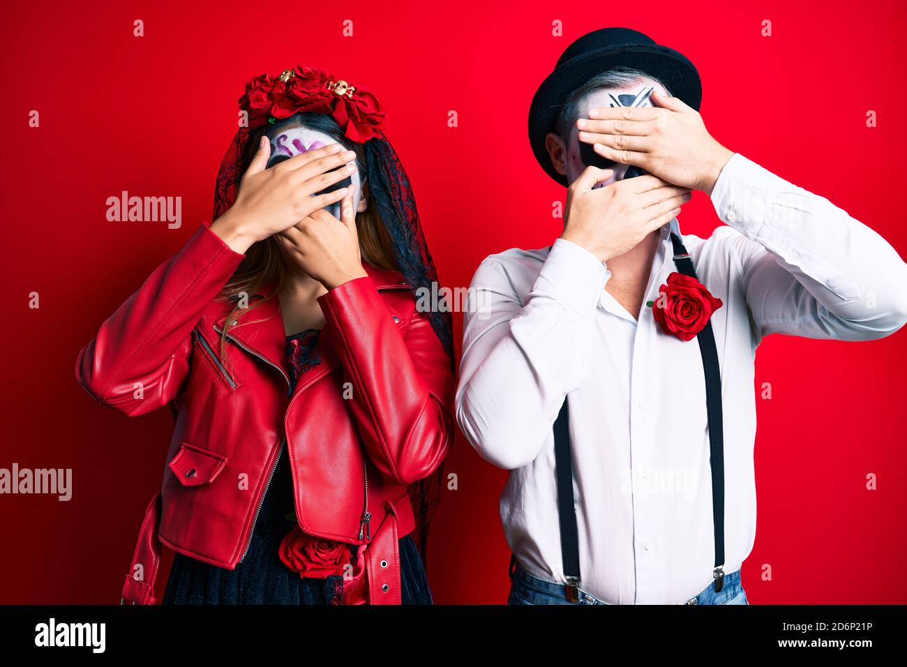 Coppia indossando giorno del costume morto sopra occhi rossi e la bocca con le mani, sorpresi e scioccati. Nascondere emozione Foto Stock