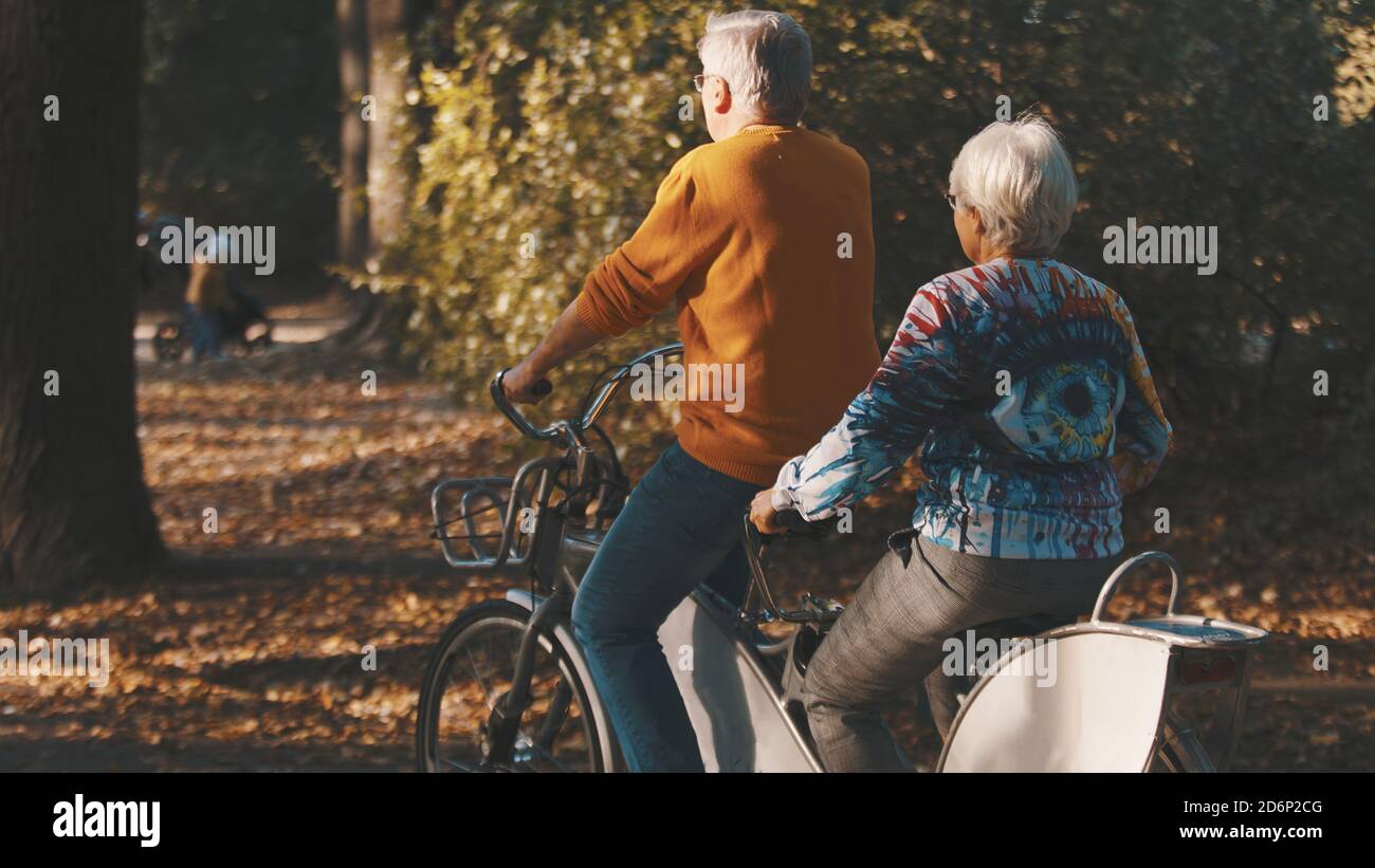 Coppia senior in bicicletta doppia in autunno. Nonna e nonno in bicicletta insieme . Anziani stile di vita sano e attivo. Foto di alta qualità Foto Stock