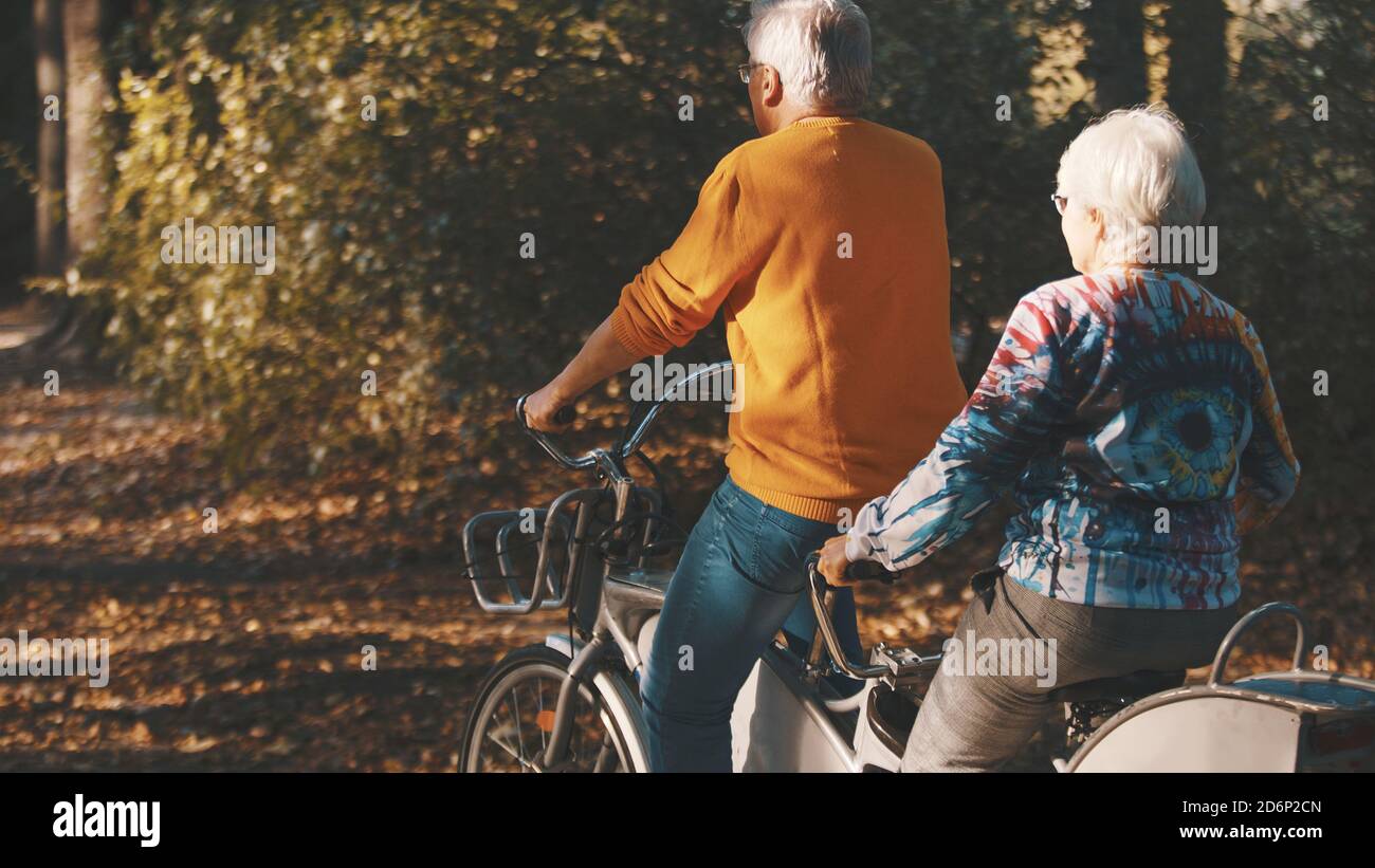 Coppia senior in bicicletta doppia in autunno. Nonna e nonno in bicicletta insieme . Anziani stile di vita sano e attivo. Foto di alta qualità Foto Stock