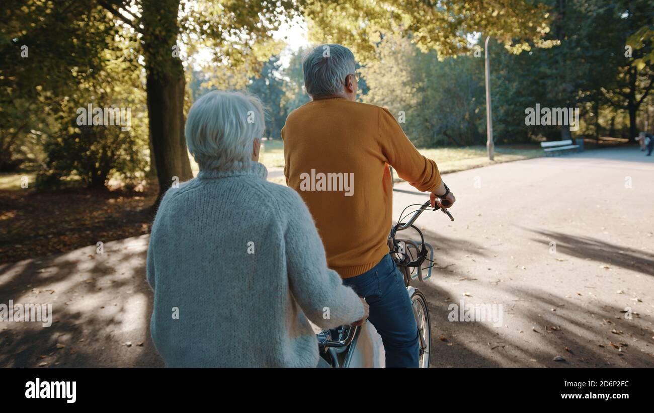 Coppia senior in bicicletta doppia in autunno. Nonna e nonno in bicicletta insieme . Anziani stile di vita sano e attivo. Foto di alta qualità Foto Stock