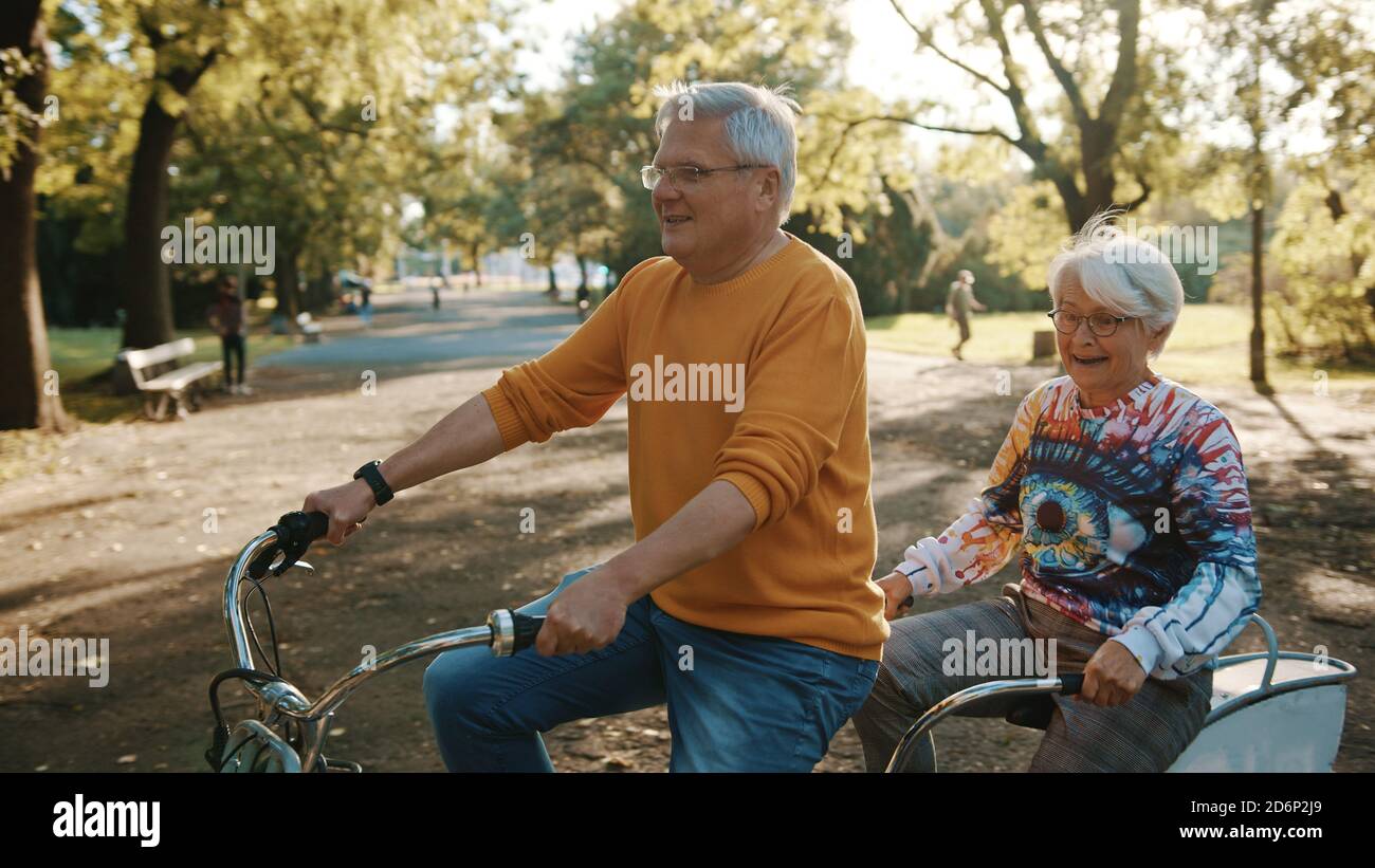 Coppia senior in bicicletta doppia in autunno. Nonna e nonno in bicicletta insieme . Anziani stile di vita sano e attivo. Foto di alta qualità Foto Stock