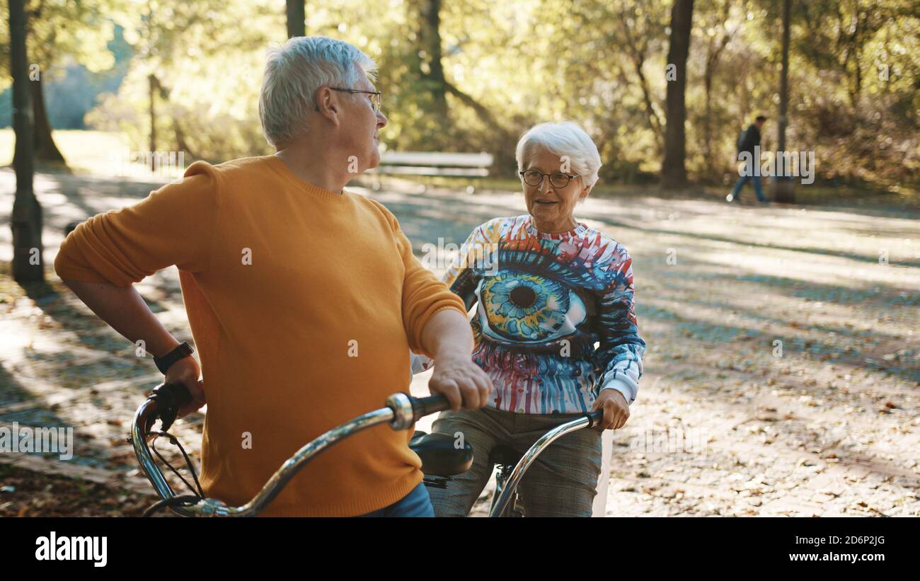 Coppia senior in bicicletta doppia in autunno. Nonna e nonno in bicicletta insieme . Anziani stile di vita sano e attivo. Foto di alta qualità Foto Stock