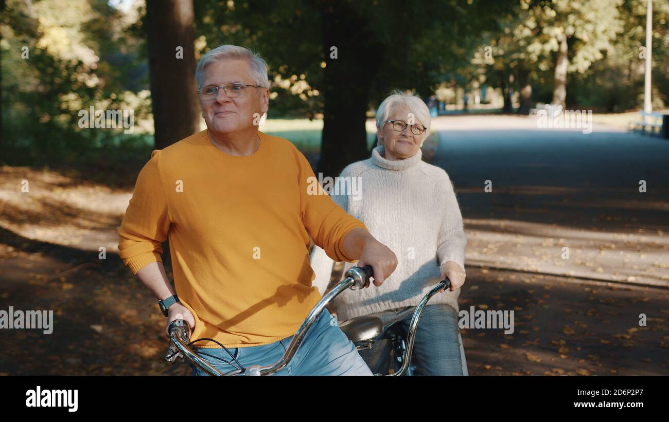 Coppia senior in bicicletta doppia in autunno. Nonna e nonno in bicicletta insieme . Anziani stile di vita sano e attivo. Foto di alta qualità Foto Stock