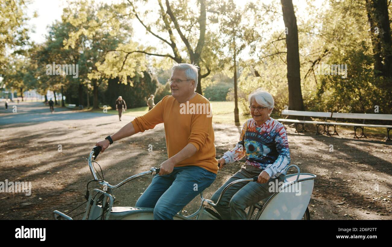 Coppia senior in bicicletta doppia in autunno. Nonna e nonno in bicicletta insieme . Anziani stile di vita sano e attivo. Foto di alta qualità Foto Stock