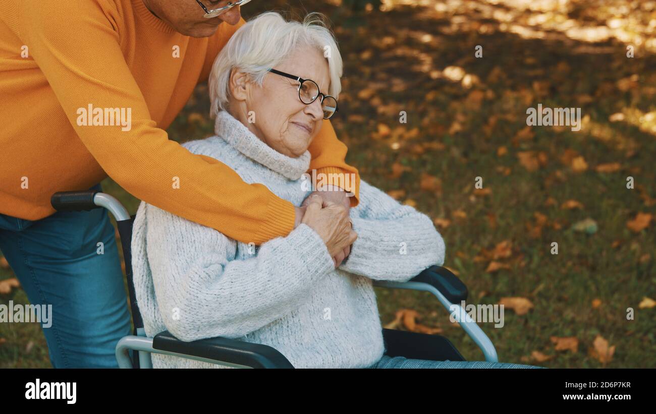 Vecchia coppia che ha una romantica giornata d'autunno nella foresta. Abbracciando l'albero e sorridendo. Foto di alta qualità Foto Stock