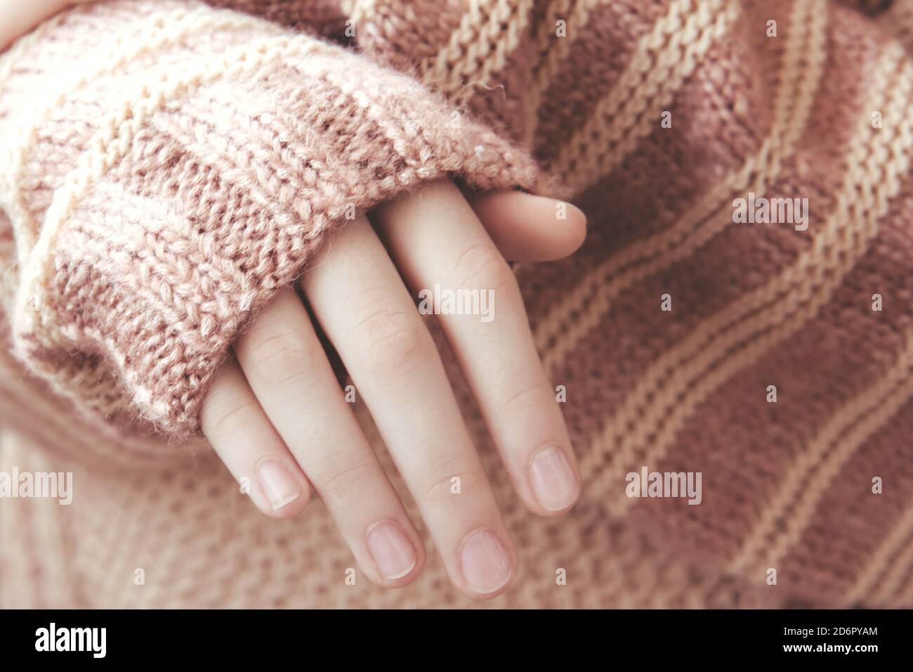 Donna in un morbido pullover a maglia tiepida beige ha piegato le mani alla luce del sole. Autunno presto Foto Stock