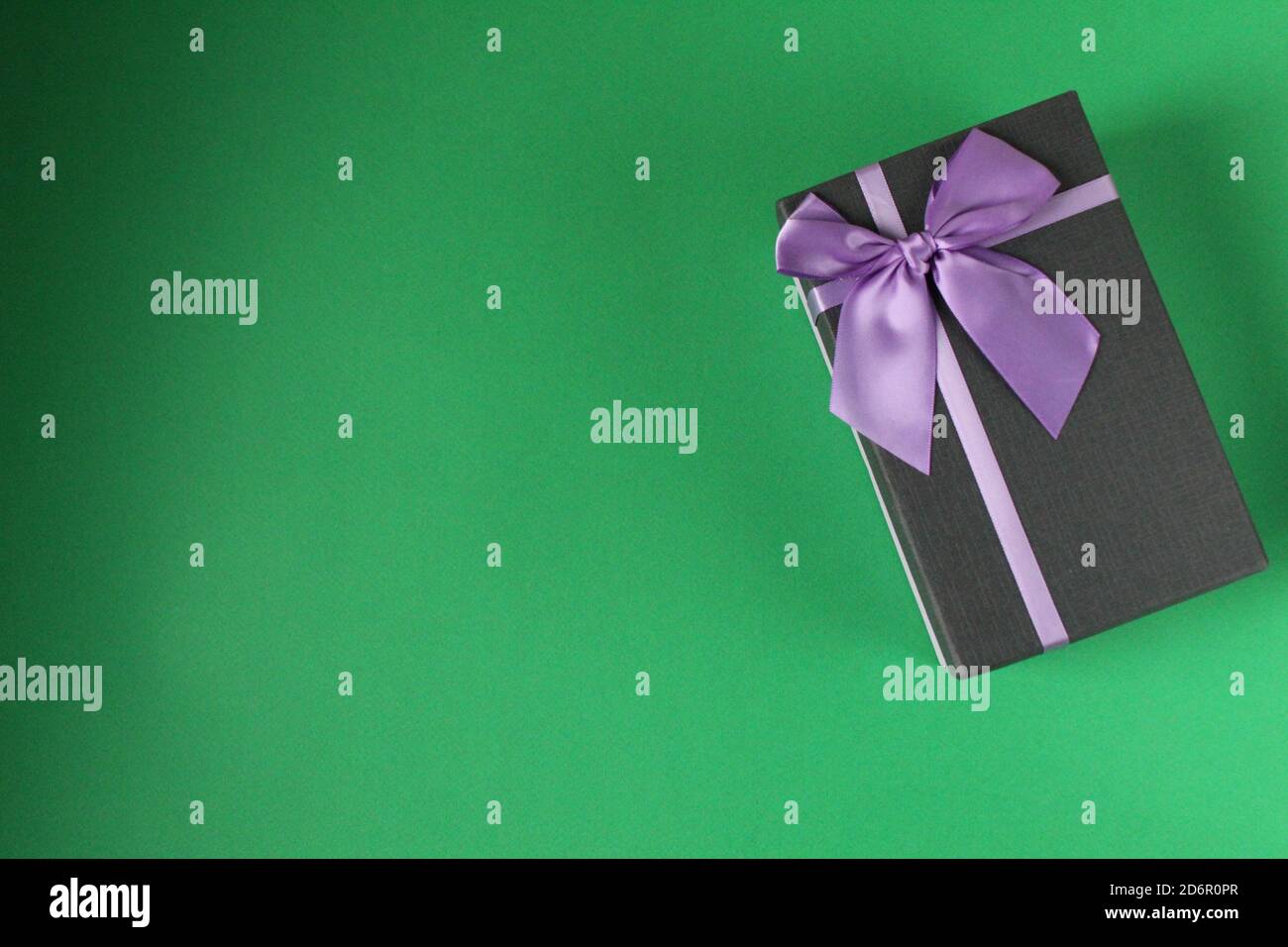 Festa di Natale di Capodanno festa della mamma San Valentino compleanno anniversario confezione regalo nera con viola fucsia colori con a. prua su un verde Foto Stock