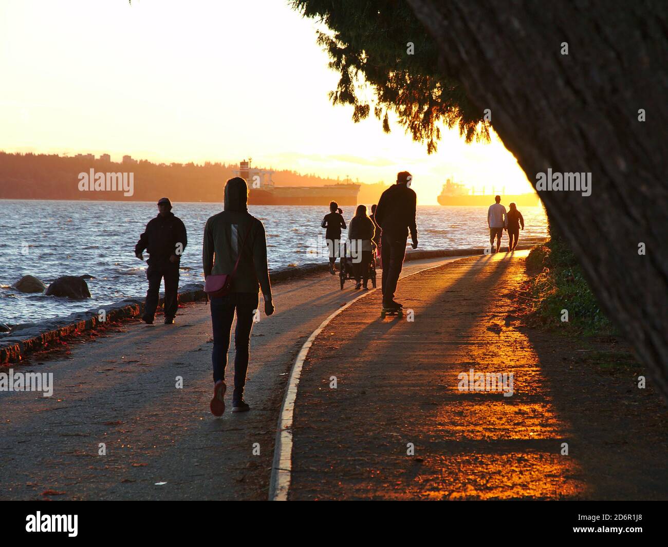 Ottobre 2020, Vancouver, Canada - persone che camminano, corrono e jogging lungo il muro di mare di Stanley Park. Navi ancorate visibili sullo sfondo. Foto Stock