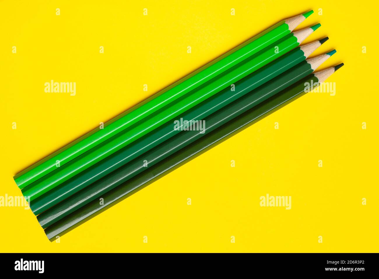 matite diagonali di legno verde affilato su sfondo giallo brillante, isolate, spazio copia, mock-up Foto Stock