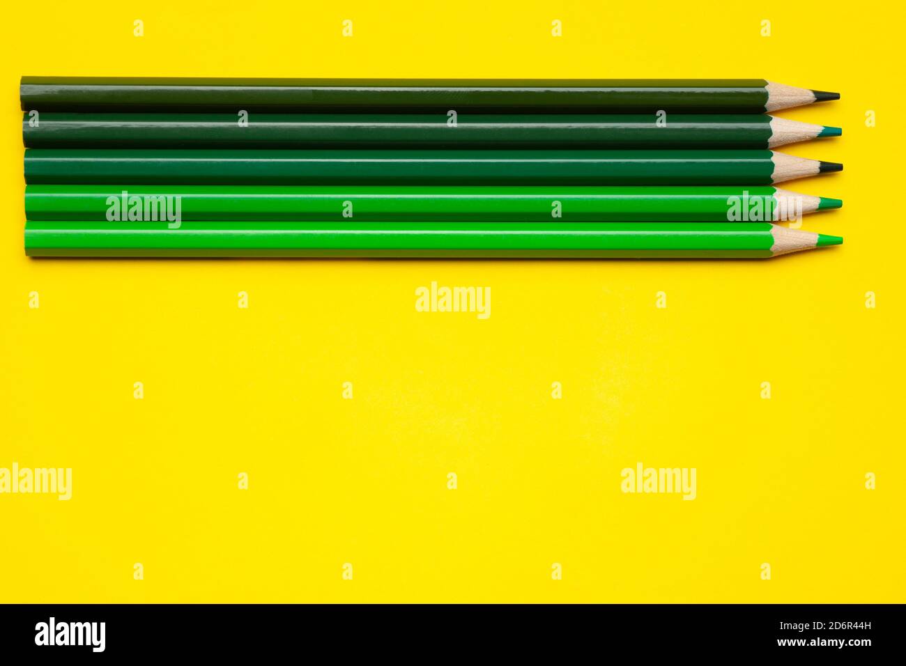matite orizzontali verdi in legno affilato su sfondo giallo brillante, isolate, spazio copia, mock-up Foto Stock