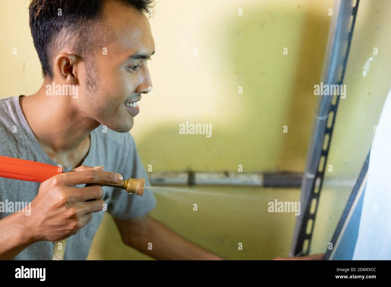 I giovani usano uno spruzzatore per staccare la gomma sul setscreen, il processo di produzione di pellicole sul setkscreen Foto Stock