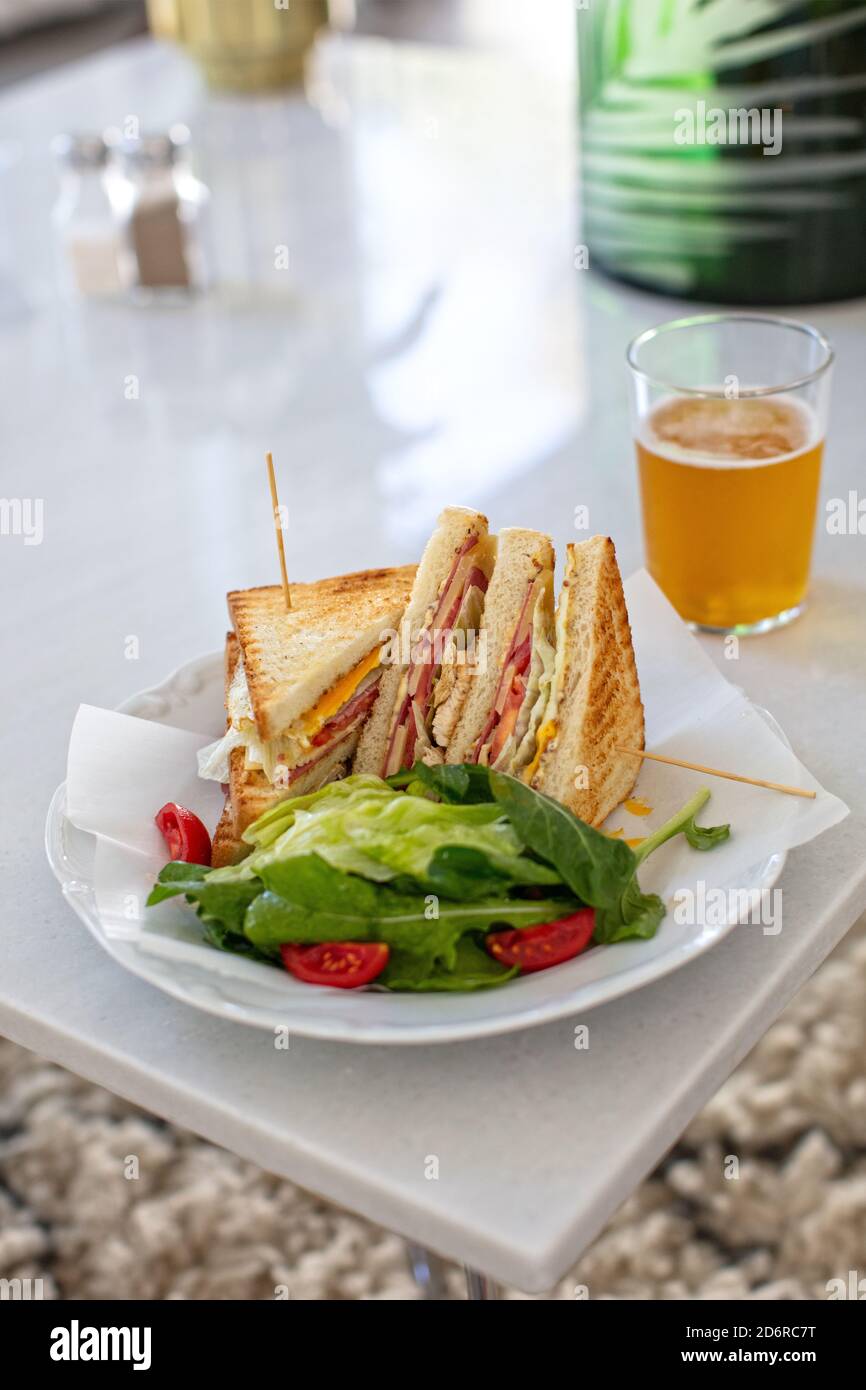 Club Sandwich con un bicchiere di birra su un tavolo. Fast food Foto Stock