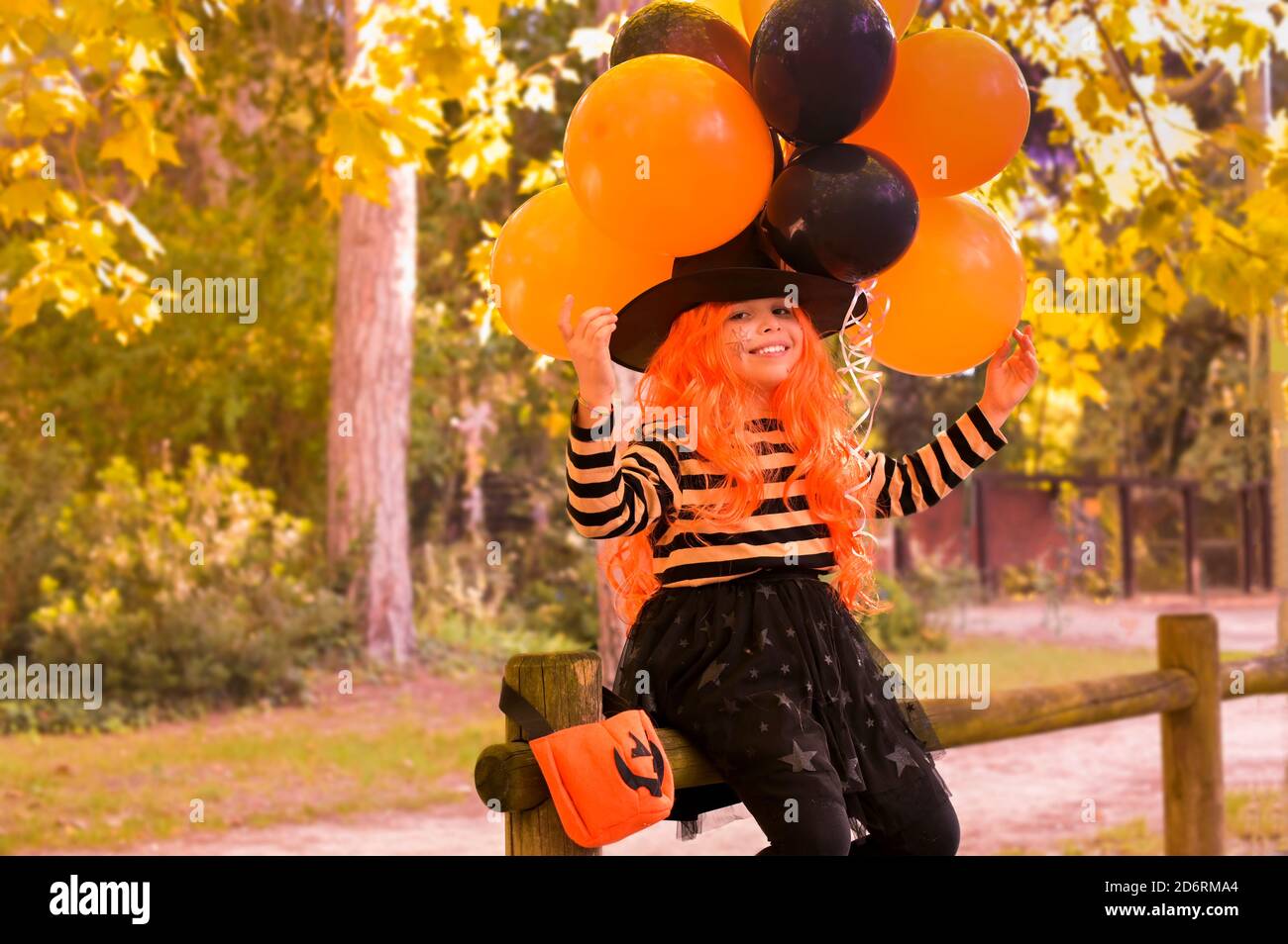 Halloween per bambini. Bambina nel parco autunnale. Un bambino in un costume di carnevale su Halloween con grandi palloncini colorati. La messa a fuoco viene spostata in modo morbido sull'oggetto principale. Spazio di copia. Foto Stock