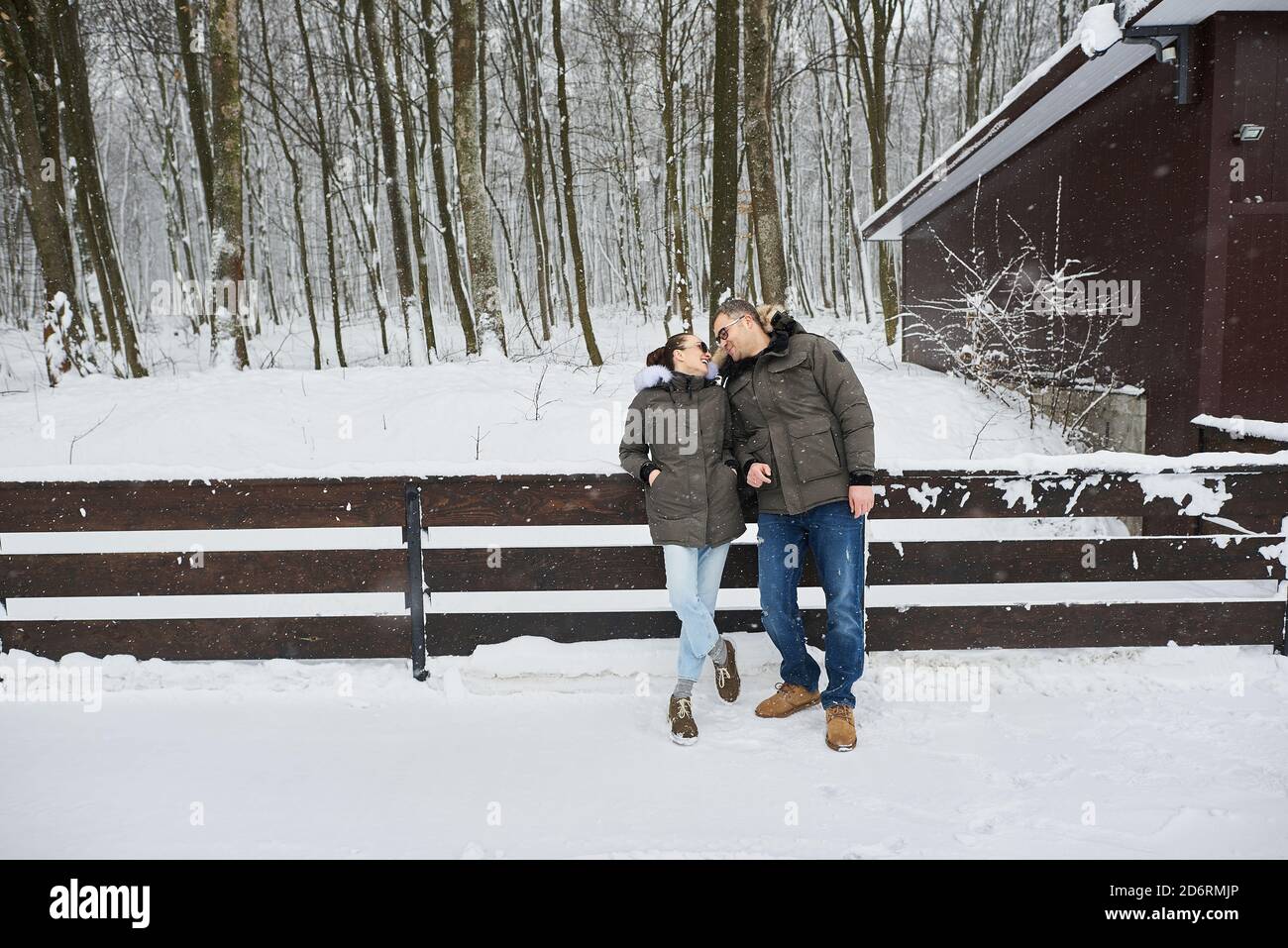 Una bella giovane coppia innamorata camminando attraverso il parco invernale in nevicata Foto Stock