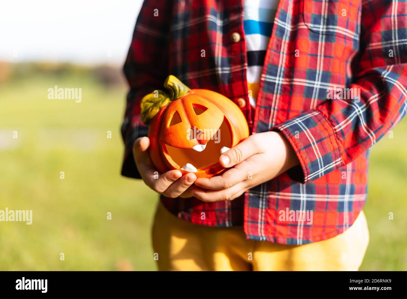 Mano del capretto che tiene la lampada della zucca di Jack'o, trucco o trucco il giorno di Halloween. Concetto per le vacanze autunnali background Foto Stock