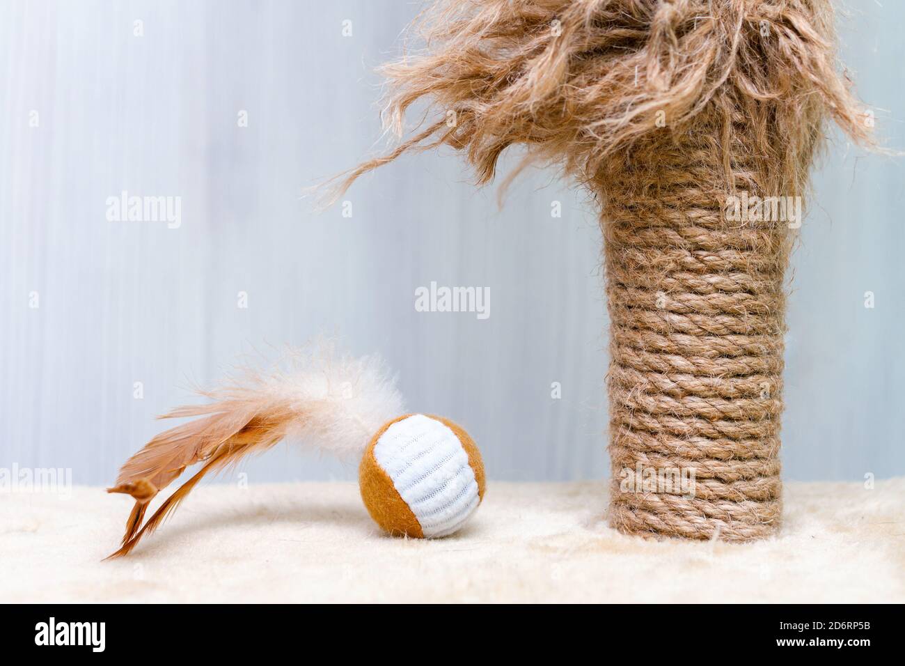 usato gatto graffiando palo e gatto giocattolo palla con piume su sfondo bianco Foto Stock