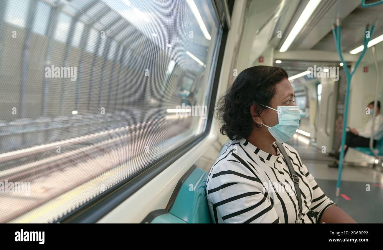 Donna che indossa una maschera facciale all'interno del treno della metropolitana. Viaggiare nuovo normale durante la pandemia. Foto Stock