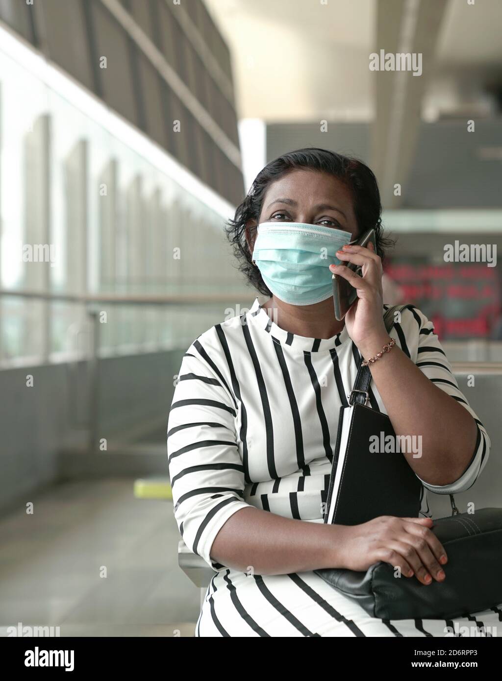 Ritratto di donna che indossa la maschera seduta e parla sul cellulare. Spazio di copia. Foto Stock