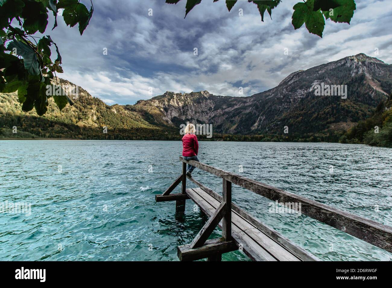 Giovane ragazza che si riposa sul lago di montagna, Austria. Donna che viaggia godendo di vista delle Alpi. Wanderlust concetto di libertà di viaggio. Avventura estiva vacanza Foto Stock