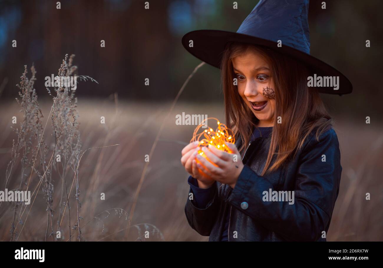 Ragazza teen carina in un costume di Halloween fuori tenendo le luci nelle sue mani. Foto Stock