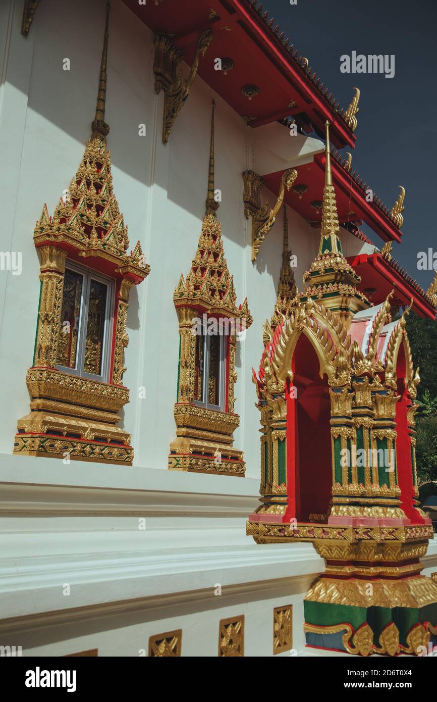 Thailandia, Phuket - 2019. Wat Suwan Khiri Khet. Persiane dorate sulle finestre e pareti dipinte Foto Stock