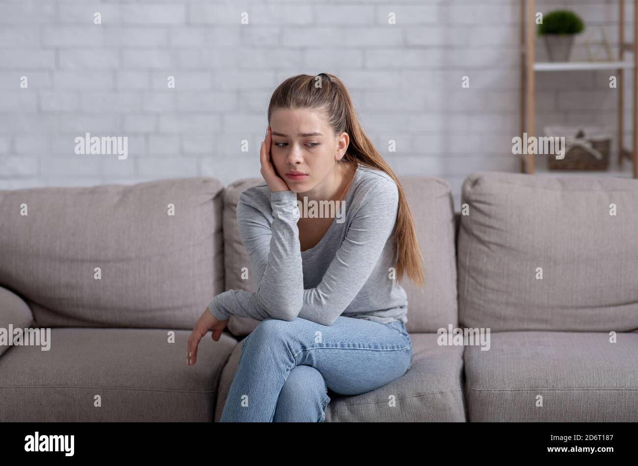 Concetto di salute mentale. Giovane donna che ha depressione sul divano a casa Foto Stock