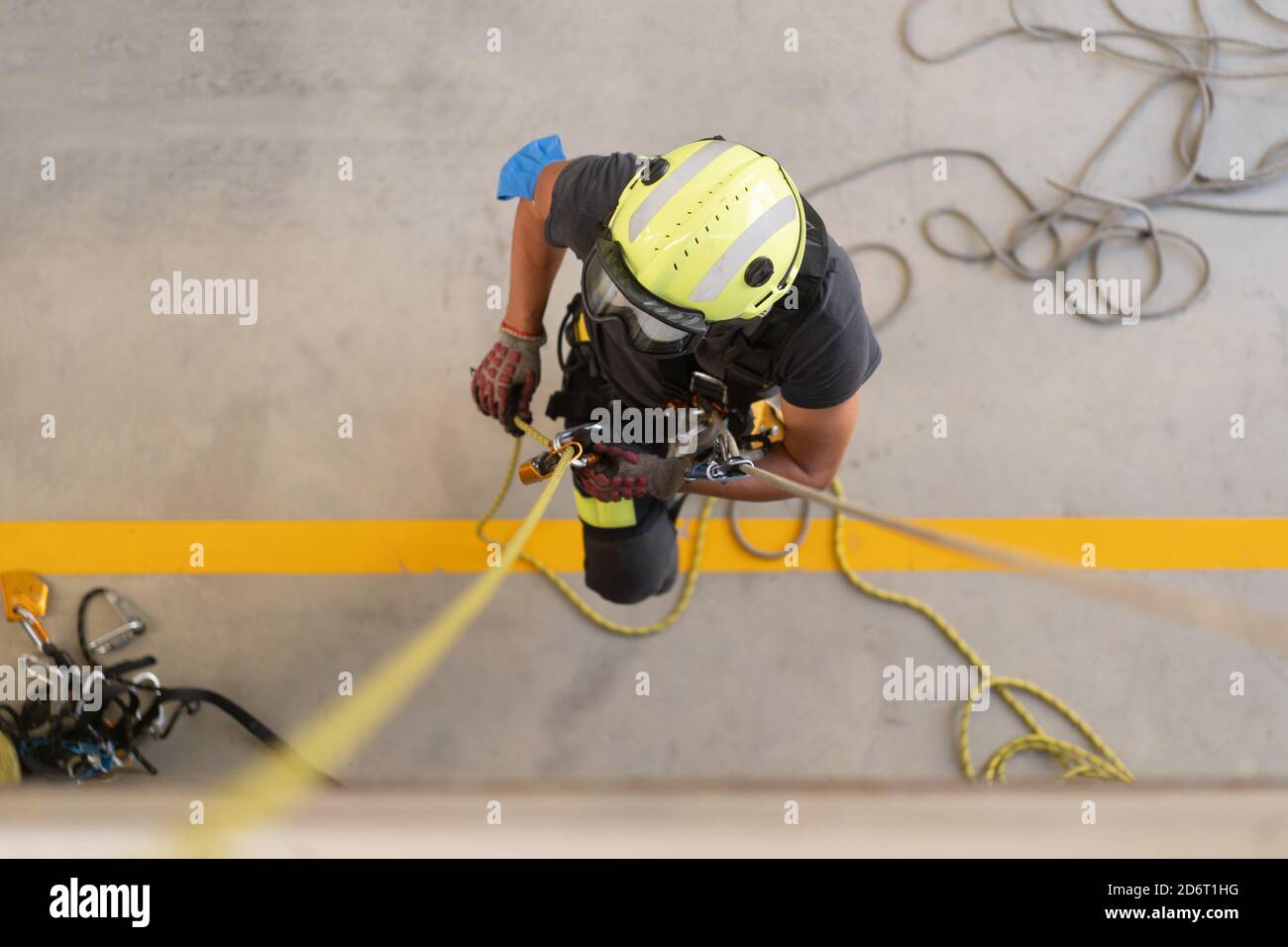 Dall'alto di irriconoscibile pompiere in casco protettivo brillante messa su guanti resistenti al calore vicino a funi allungate durante le pratiche di routine Foto Stock