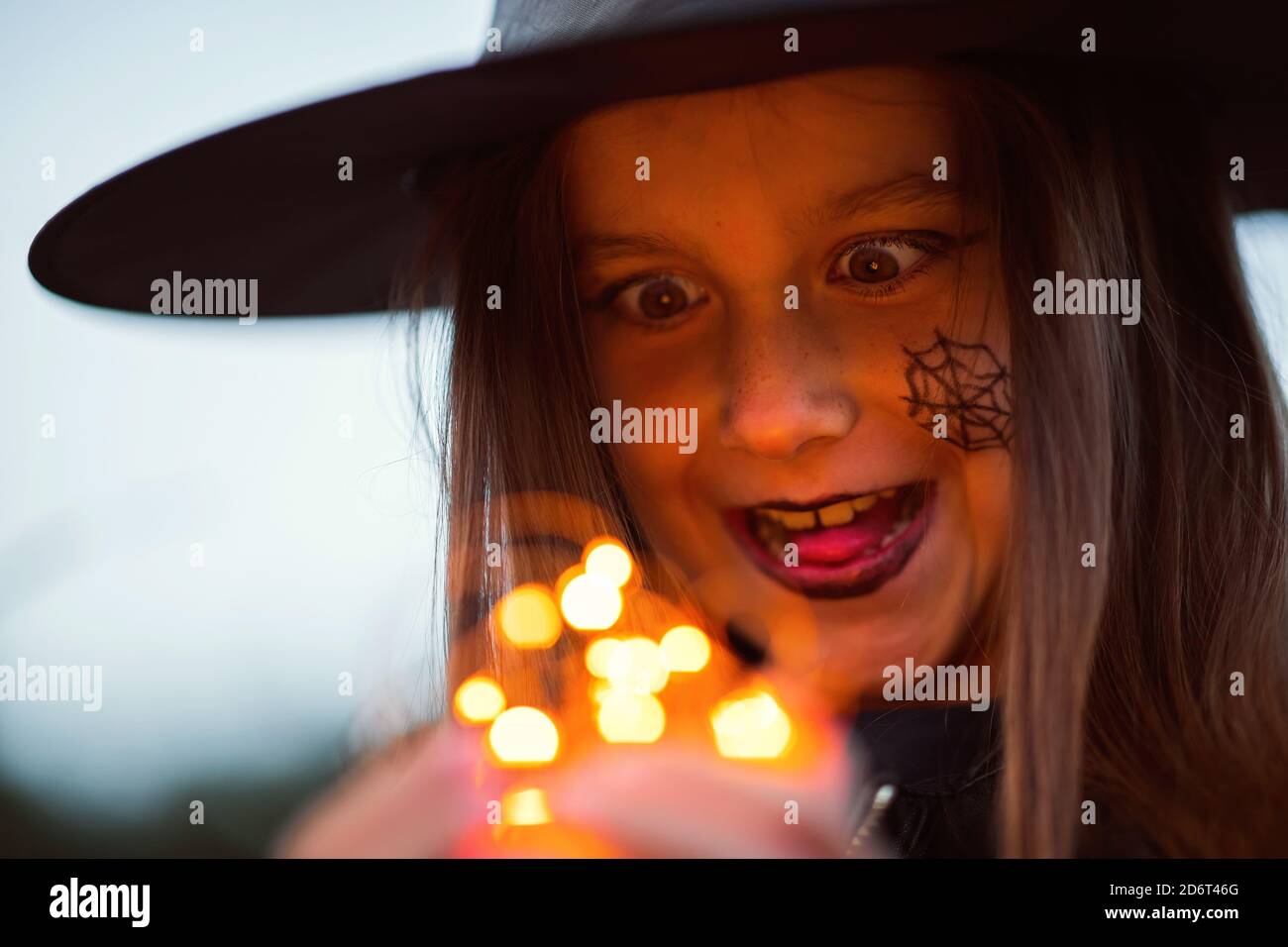 Ragazza teen carina in un costume di Halloween fuori tenendo le luci nelle sue mani. Foto Stock