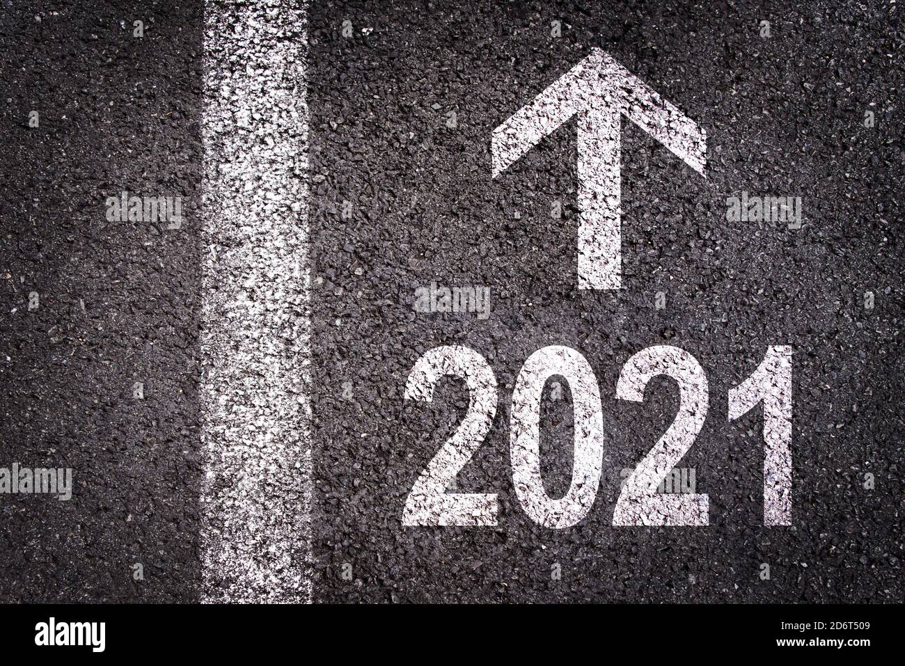 2021 e una freccia di direzione scritta su un fondo stradale asfaltato, biglietto d'auguri urbano di nuovo anno Foto Stock