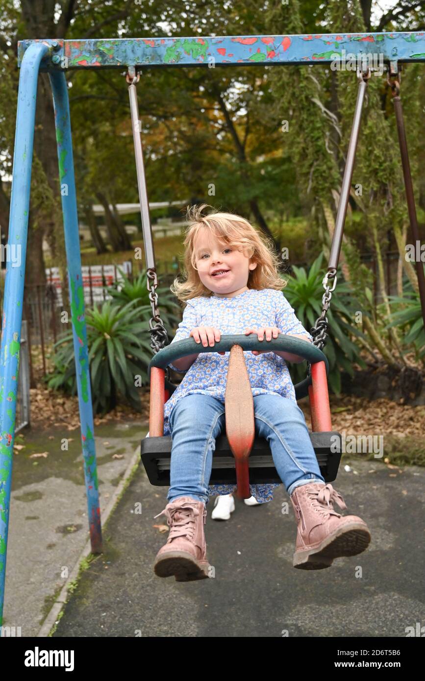 Giovane ragazza di 3 anni che gioca nel parco locale Un swing Brighton UK Foto Stock