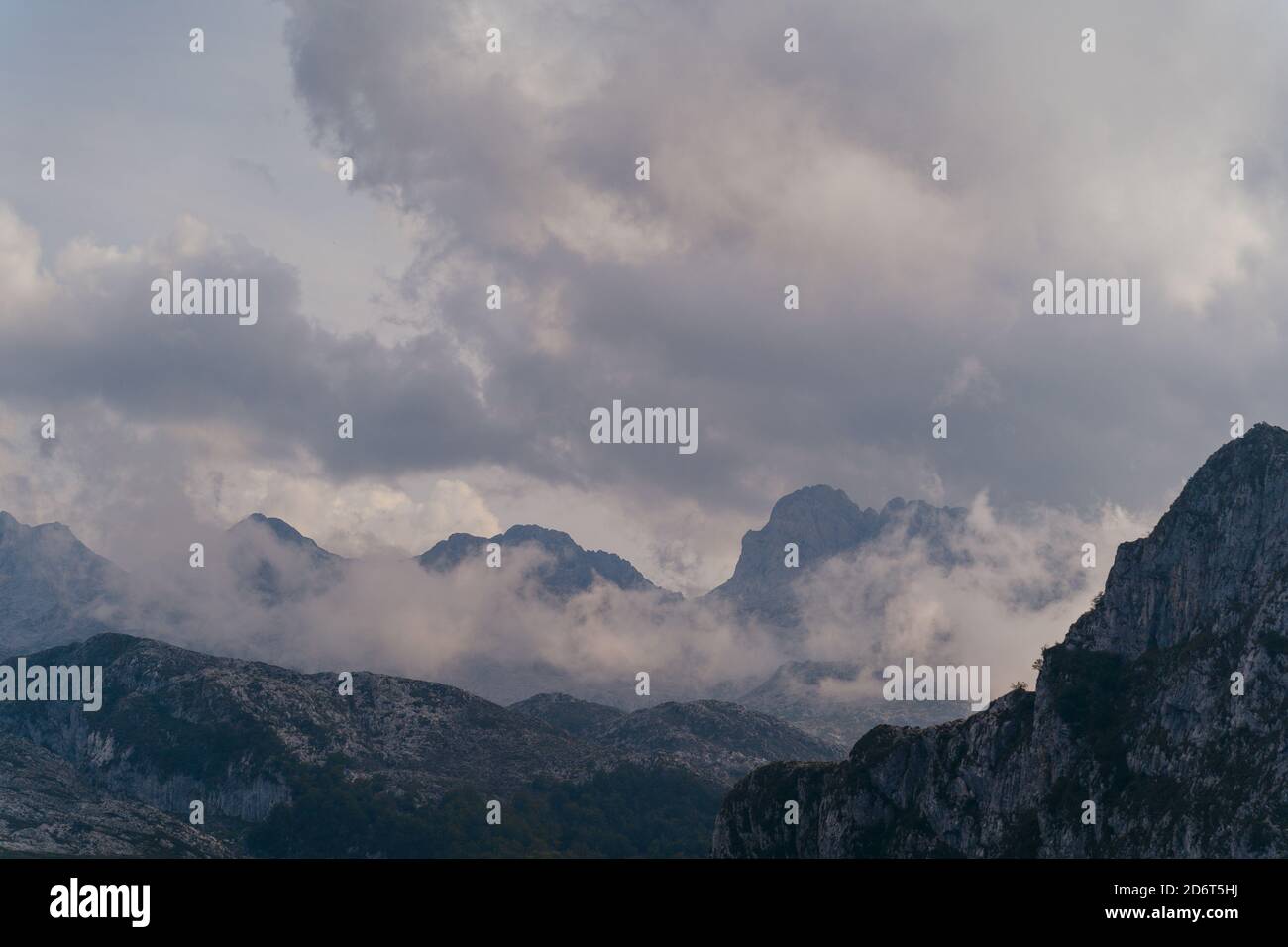 Vista panoramica di un'enorme catena montuosa rocciosa con le vette nuvole bianche e pesanti situate nelle tranquille alture del giorno di copertura Foto Stock