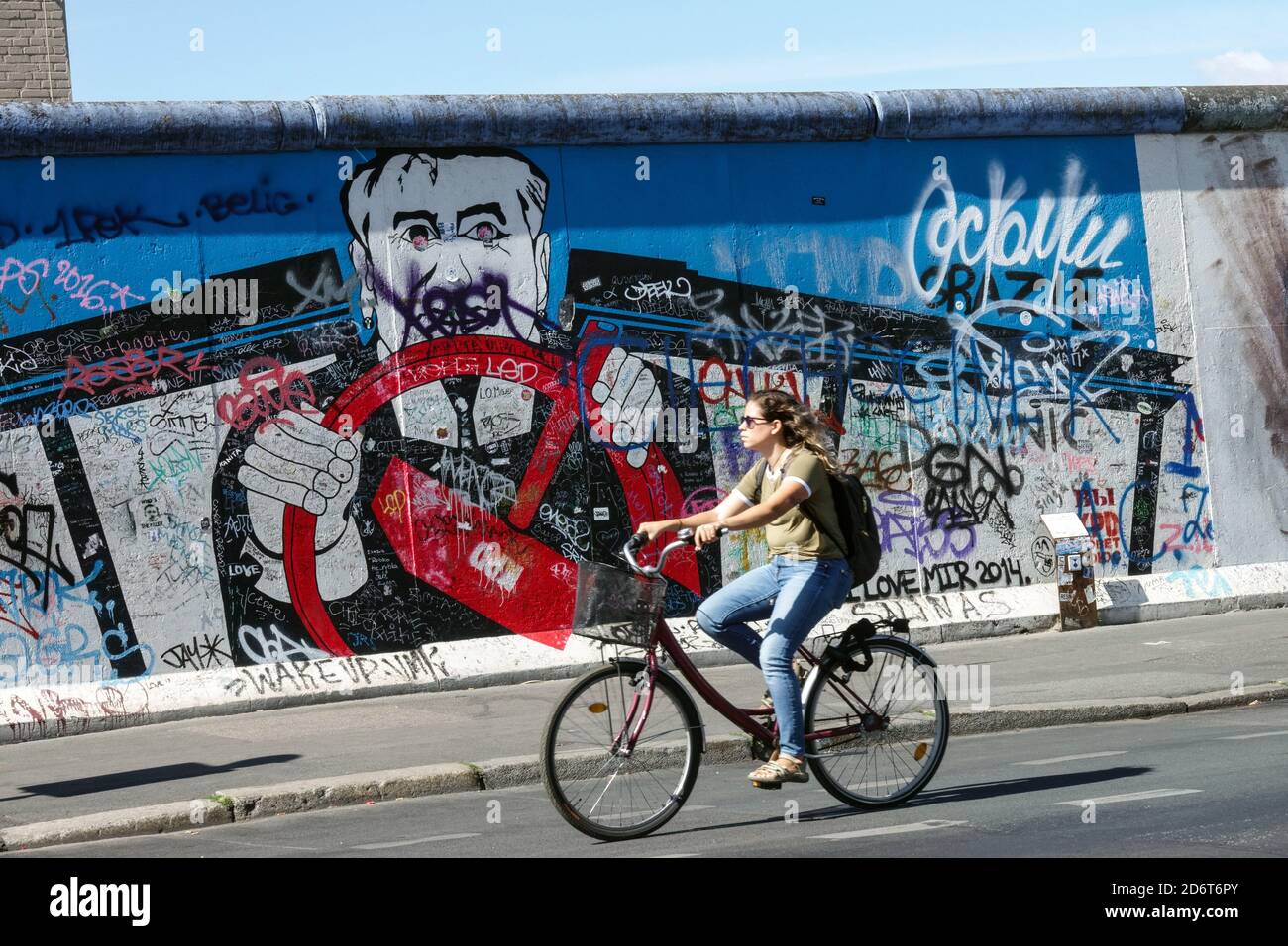 Graffiti del muro di Berlino East Side Gallery arte di strada Berlino Donna giro in bicicletta Germania Friedrichshain città arte di strada Berlino bicicletta muro Foto Stock
