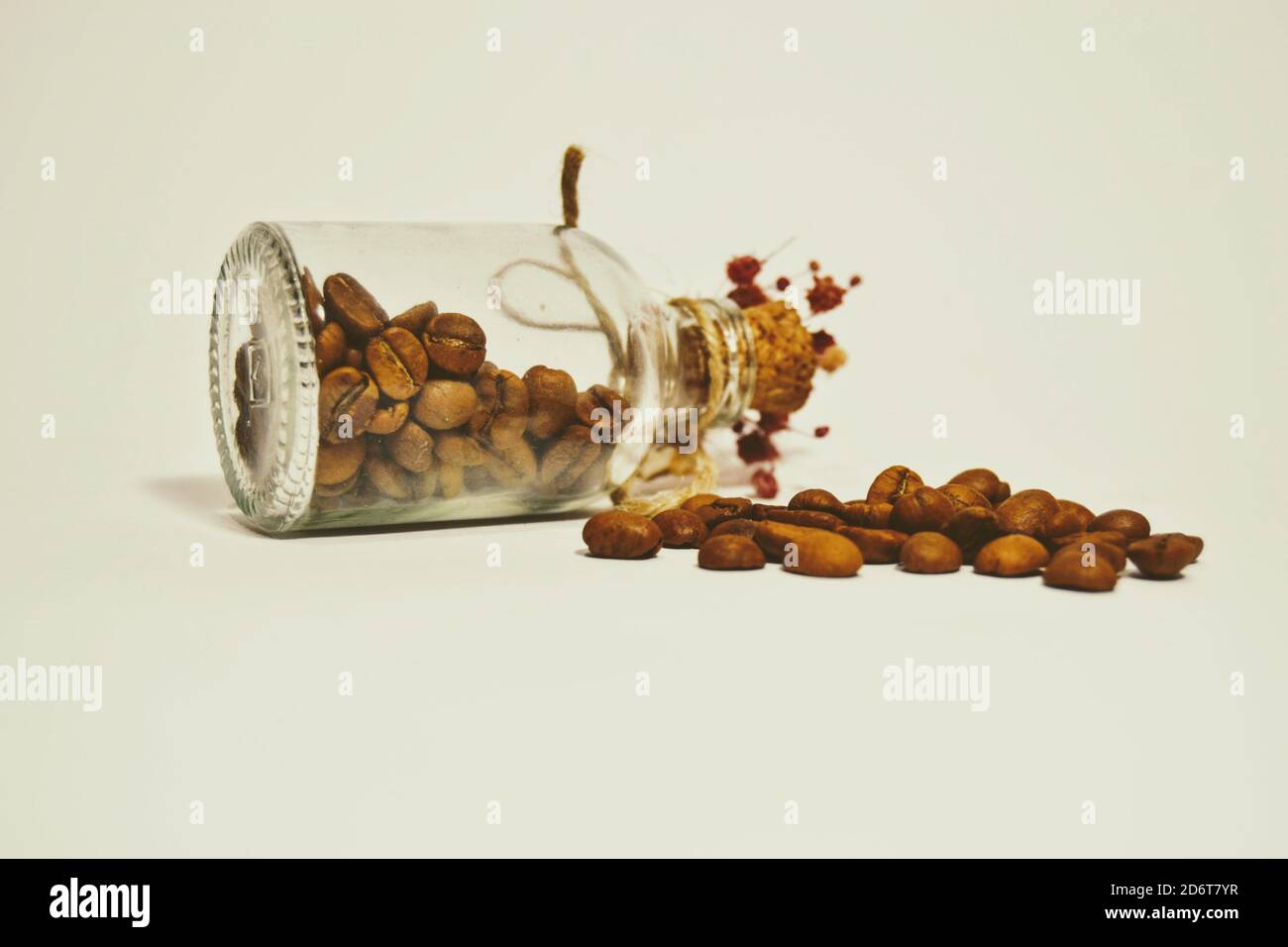 Chicchi di caffè freschi e secchi su sfondo isolato. Carino e piccolo vaso e tappo vino vecchio stile con fiori artificiali. Foto Stock