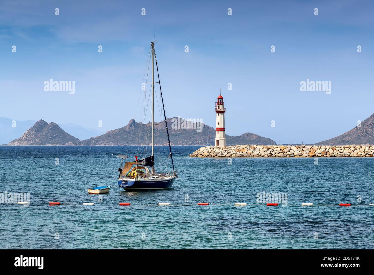 Faro in porto con yacht in giornata di sole Foto Stock