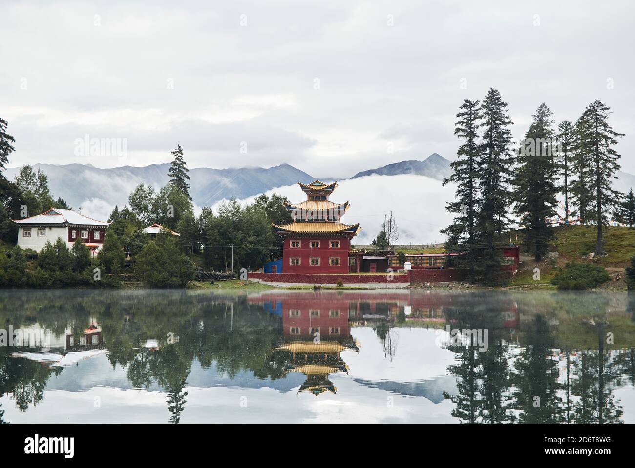 Pittoresco scenario di tempio buddista situato sulla riva della calma Lago Cuoka con superficie d'acqua riflettente nella provincia dell'altopiano cinese Foto Stock