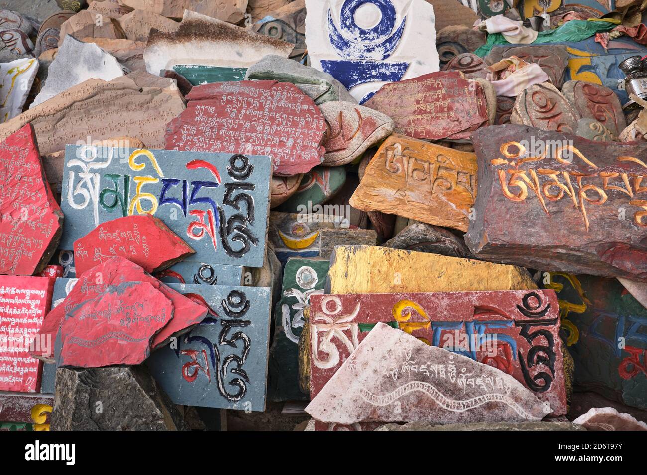 Vista dall'alto del mantra sanscrito Om mani Padme Hum inciso sulla superficie scabra di lastre di pietra multicolore di giorno Foto Stock