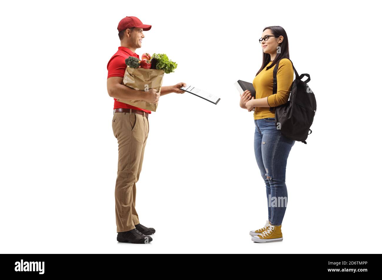 Foto di profilo a lunghezza intera di un addetto alla consegna che tiene generi alimentari in un sacchetto di carta e dando un documento ad un studentessa isolata su sfondo bianco Foto Stock