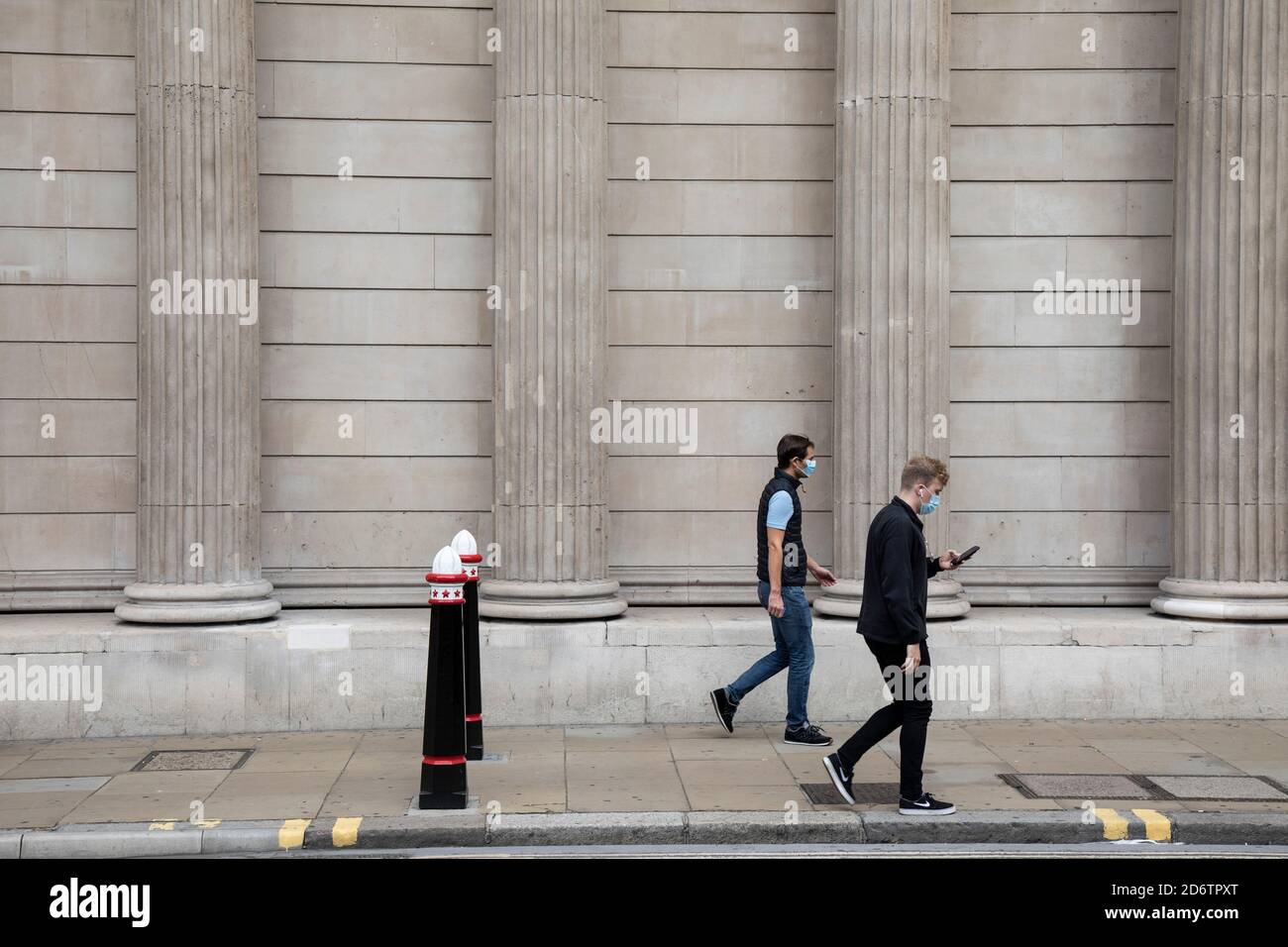 Le persone che indossano maschere passano le colonne della Bank of England nel quartiere finanziario della City of London, che è ancora molto tranquillo con poche persone intorno e che lavorano a causa dell'epidemia di Coronavirus, mentre il blocco continua il 9 settembre 2020 a Londra, Regno Unito. Foto Stock