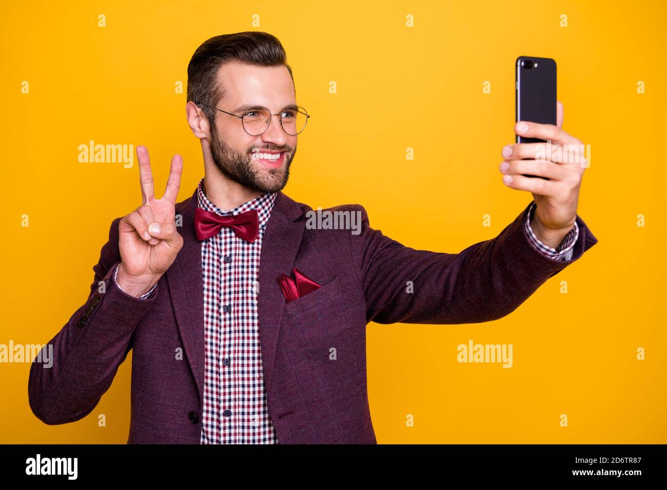 Foto di bei vestiti eleganti ragazzo attraente uomo d'affari tenere  telefono che fa selfie che mostrano il simbolo di v-segno buone specifiche  di abbigliamento umore cravatta camicia ad arco Foto stock -