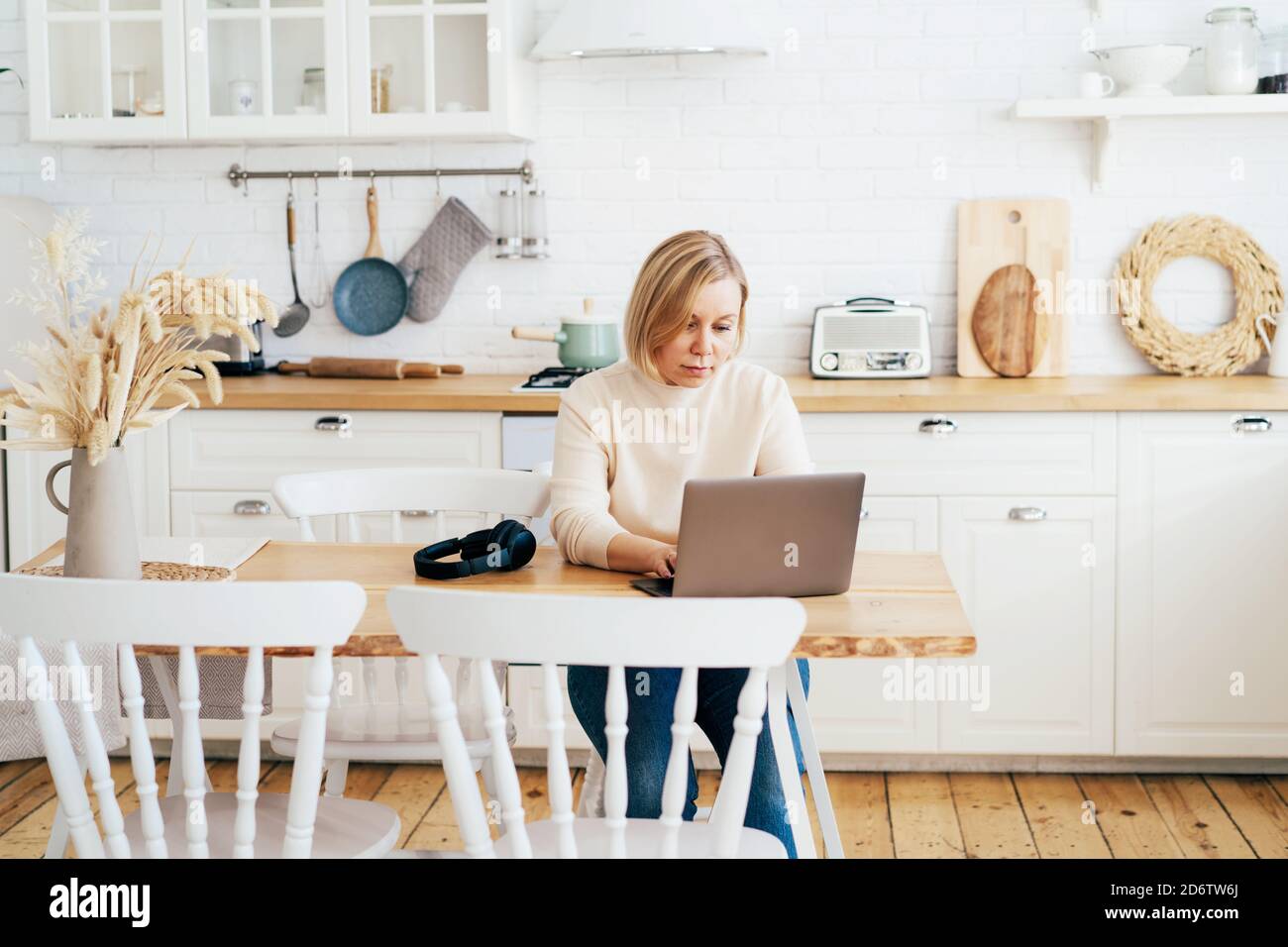 donna che lavora su un computer portatile in cucina Foto Stock
