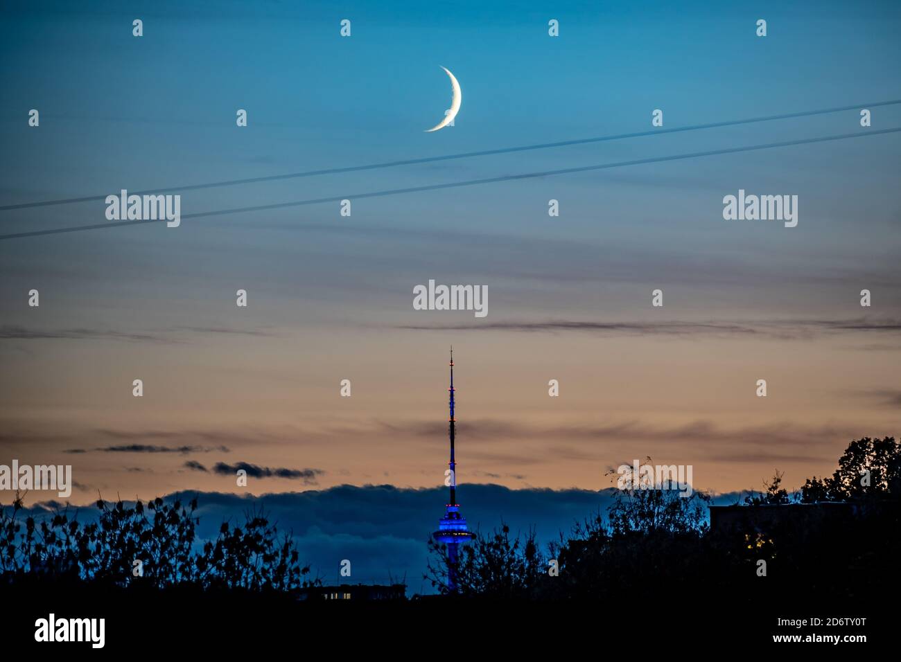 Bellissimo tramonto arancione e blu con la luna nuova sulla città e Vilnius torre della TV, Lituania Foto Stock