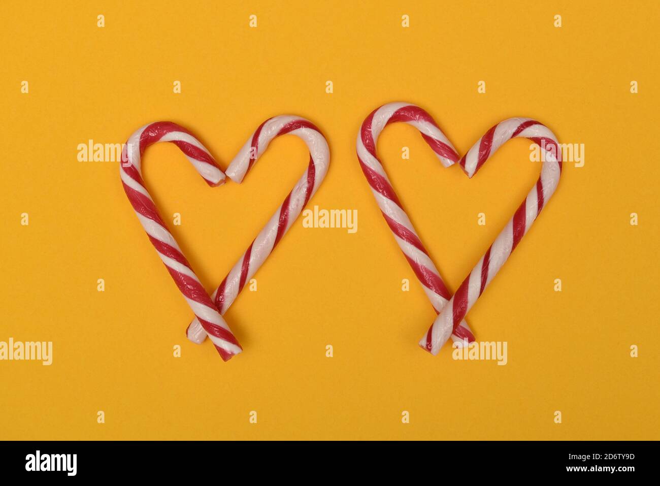 fotografia di due canne caramelle a forma di cuori su un sfondo rosso Foto Stock