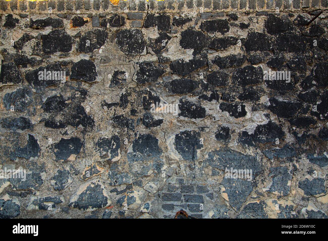 Struttura della parete di pietra contaminata da rifiuti Foto Stock