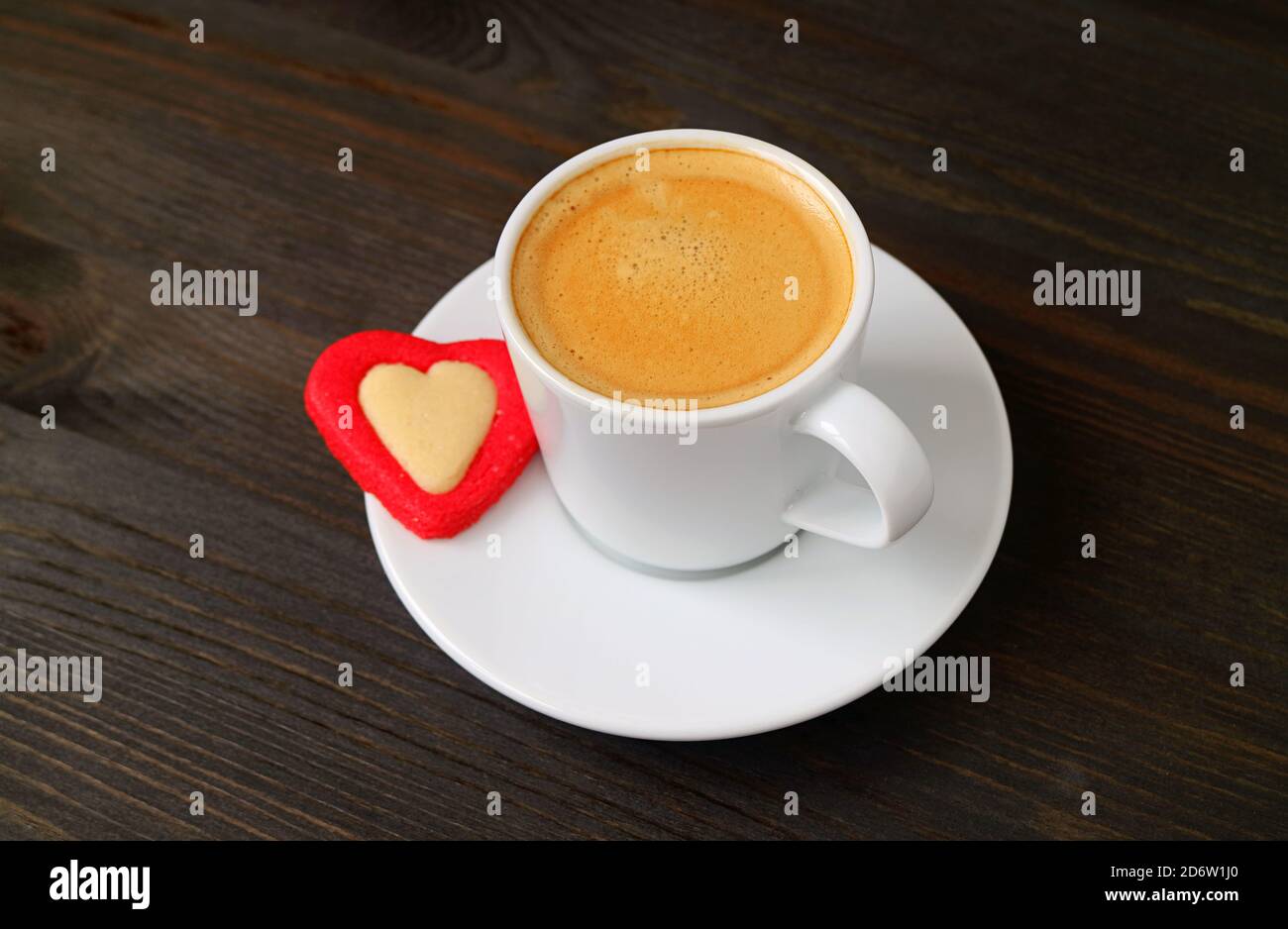 Tazza di caffè caldo con un cookie a forma di cuore Sfondo di legno marrone scuro per il concetto di San Valentino Foto Stock