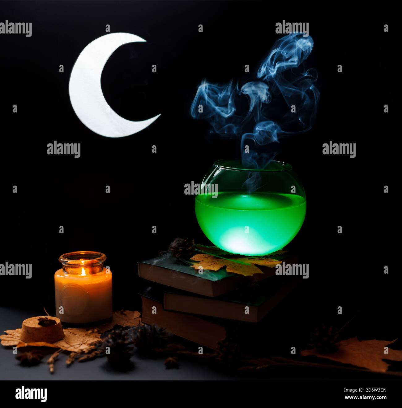 Concetto di Halloween. Recipiente trasparente in vetro con stativi di liquido verde al vapore sopra il cumulo di libri, coperto di nastro. Foto Stock